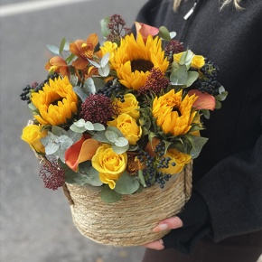 Композиция в сумке "Тональность" из подсолнухов, калл, ягод вибирнума, лимонных роз, скиммии и орхидеи в Ступино